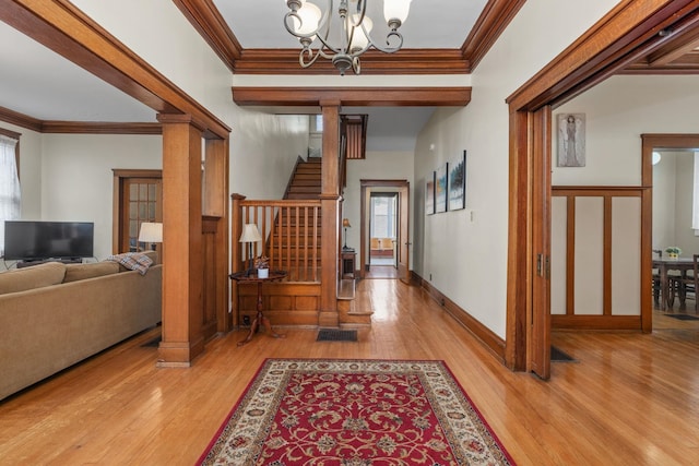 foyer with light wood-style floors, crown molding, and a chandelier