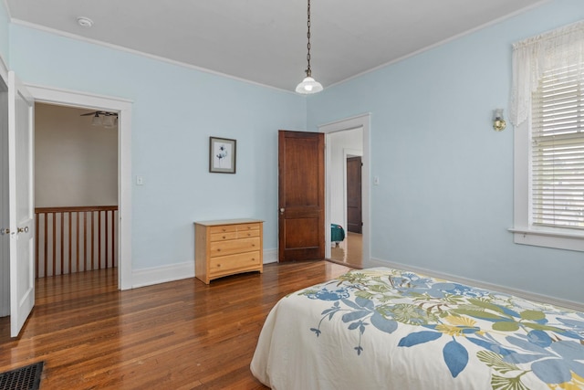 bedroom featuring crown molding, baseboards, wood finished floors, and visible vents