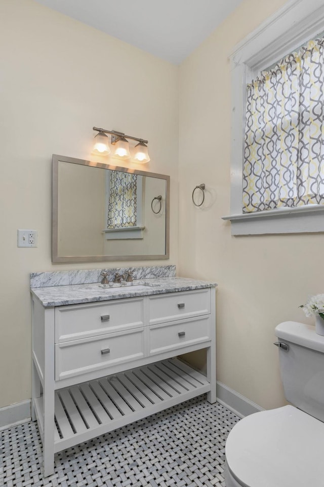 bathroom with toilet, baseboards, and vanity