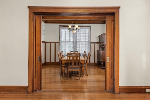 dining space featuring baseboards, an inviting chandelier, and wood finished floors
