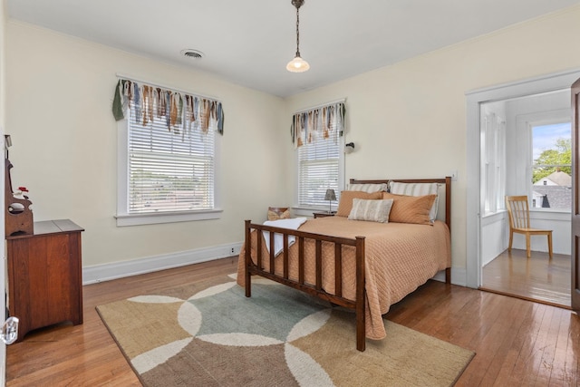 bedroom with baseboards, visible vents, and hardwood / wood-style flooring