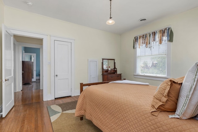 bedroom with baseboards, wood-type flooring, and visible vents