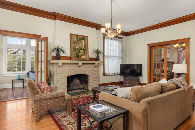 living area with crown molding, baseboards, a brick fireplace, and a notable chandelier