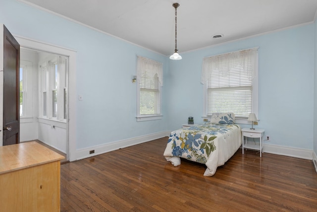 bedroom featuring baseboards, ornamental molding, wood finished floors, and visible vents