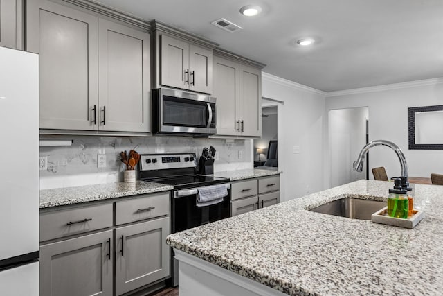 kitchen featuring light stone countertops, sink, decorative backsplash, appliances with stainless steel finishes, and ornamental molding