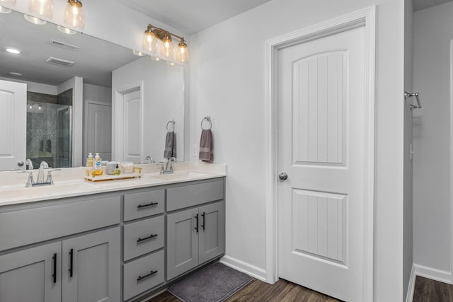 bathroom with hardwood / wood-style floors, vanity, and an enclosed shower