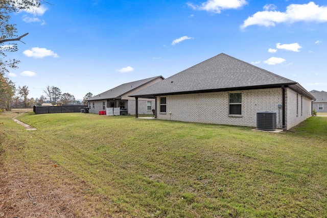 rear view of property featuring central AC unit and a yard