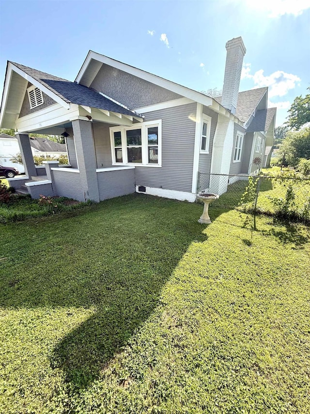  - view of property exterior with a yard, fence, a chimney, and a shingled roof