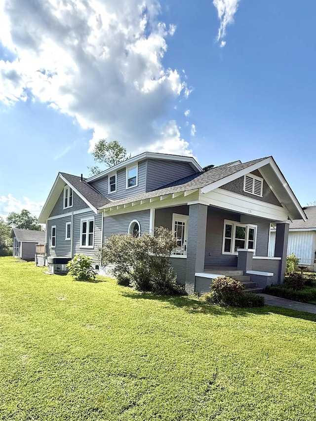- rear view of property featuring a porch, a shingled roof, and a yard