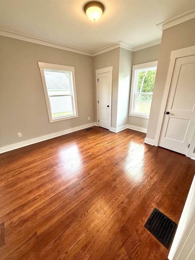  - spare room featuring baseboards, visible vents, ornamental molding, and dark wood finished floors