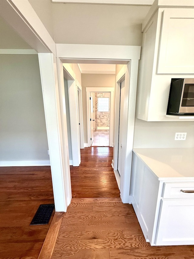  - hallway with baseboards, wood finished floors, and visible vents