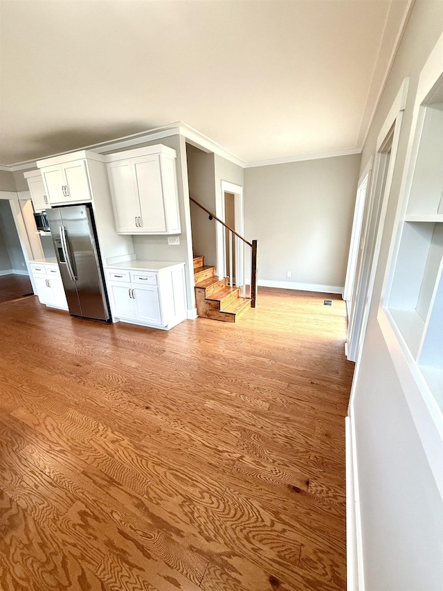  - interior space with stairs, baseboards, ornamental molding, and wood finished floors