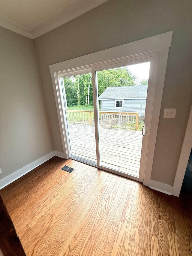  - doorway featuring baseboards, ornamental molding, light wood-type flooring, and visible vents