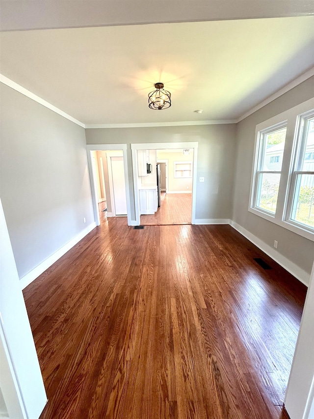  - unfurnished living room featuring baseboards, ornamental molding, dark wood finished floors, and visible vents