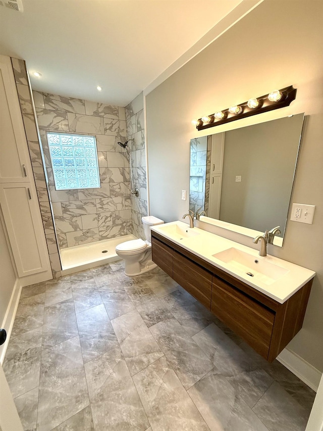  - bathroom with double vanity, a sink, toilet, and tiled shower