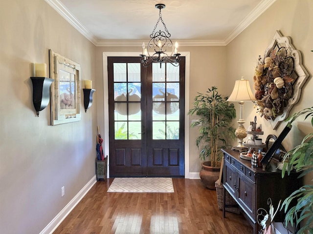 foyer entrance with an inviting chandelier, crown molding, dark wood-type flooring, and french doors