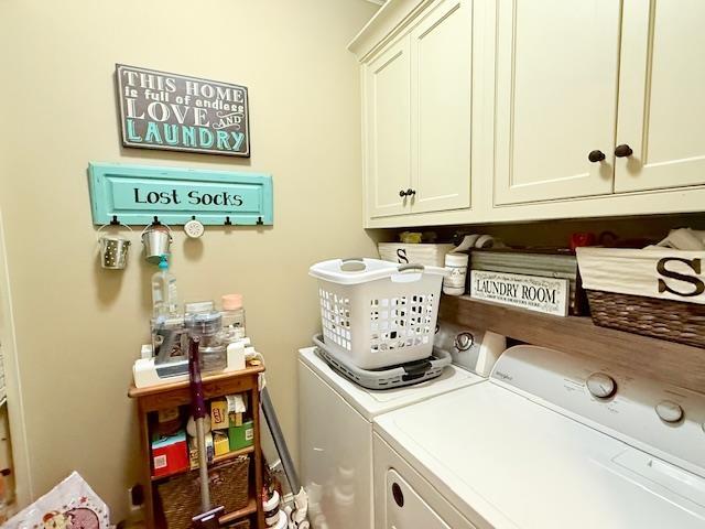 clothes washing area with washer and clothes dryer and cabinets