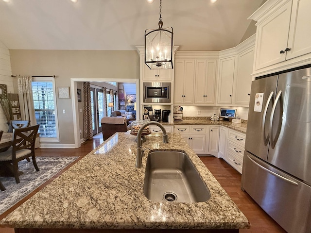 kitchen with sink, light stone countertops, an island with sink, and appliances with stainless steel finishes