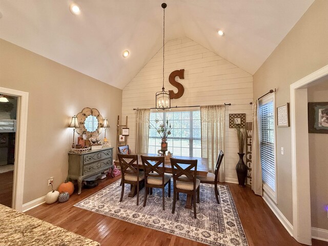 dining area with dark wood-type flooring, high vaulted ceiling, and a chandelier