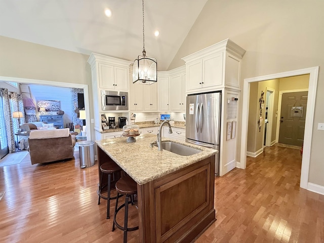 kitchen featuring white cabinets, stainless steel appliances, hanging light fixtures, and sink