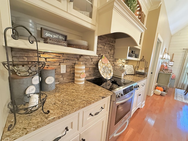 kitchen featuring premium range hood, light stone counters, stainless steel range with electric stovetop, light hardwood / wood-style floors, and white cabinetry