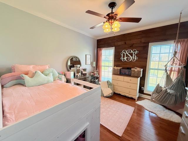 bedroom featuring wood walls, ceiling fan, dark hardwood / wood-style floors, and ornamental molding