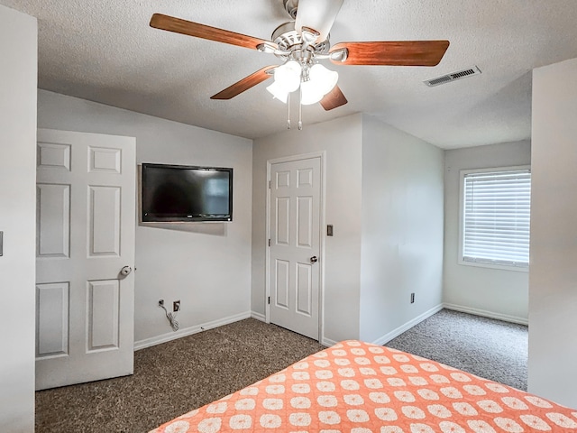 unfurnished bedroom with ceiling fan, a textured ceiling, and dark colored carpet