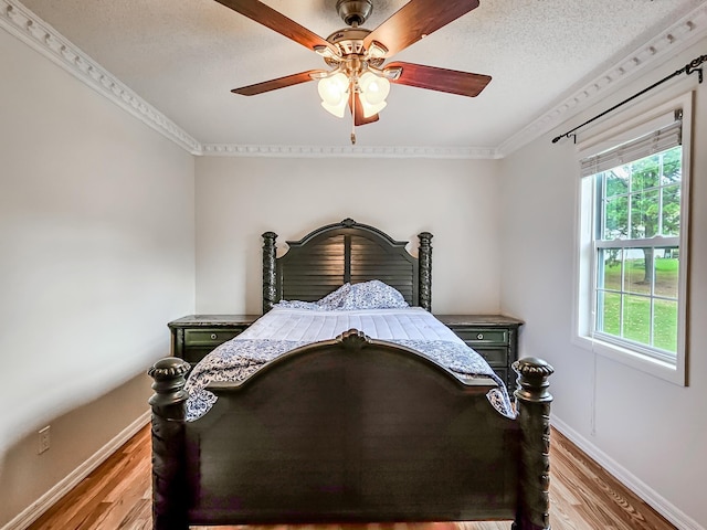 bedroom with hardwood / wood-style floors, a textured ceiling, ceiling fan, and crown molding