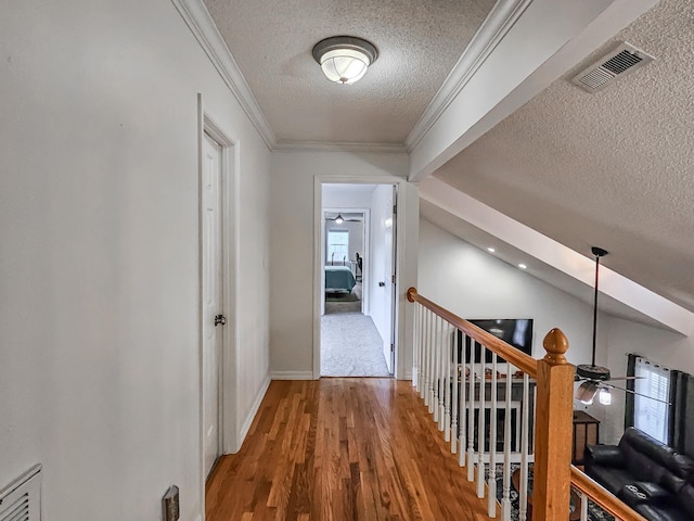 hallway with vaulted ceiling, wood-type flooring, a textured ceiling, and ornamental molding