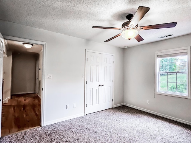 unfurnished bedroom with carpet flooring, ceiling fan, a textured ceiling, and a closet