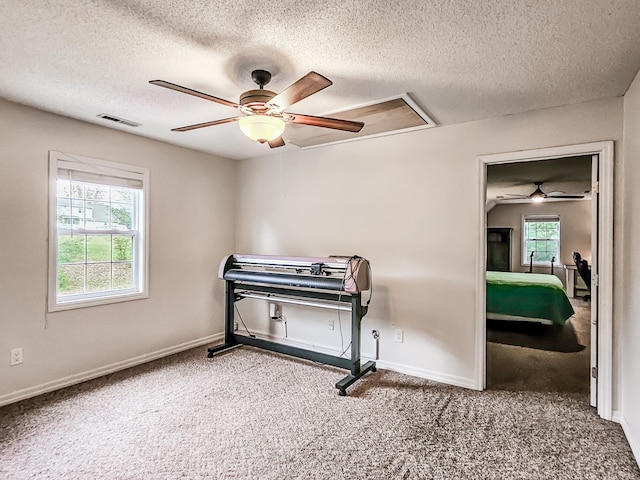 carpeted bedroom with ceiling fan and a textured ceiling