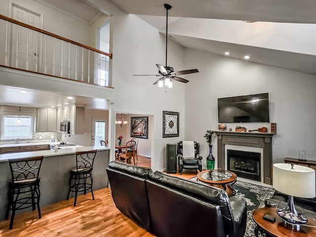 living room featuring light hardwood / wood-style floors, high vaulted ceiling, and ceiling fan