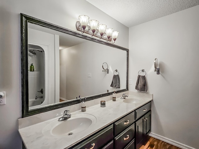 bathroom with hardwood / wood-style flooring, vanity, shower / tub combination, and a textured ceiling