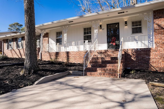 ranch-style home featuring covered porch and brick siding