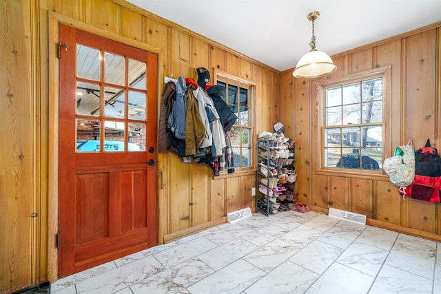 interior space featuring marble finish floor, visible vents, wooden walls, and baseboards