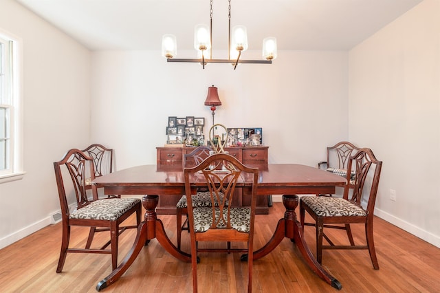 dining area with light wood-style floors, baseboards, and an inviting chandelier