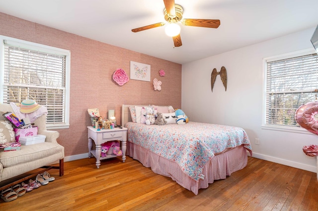 bedroom with wallpapered walls, light wood-type flooring, a ceiling fan, and baseboards