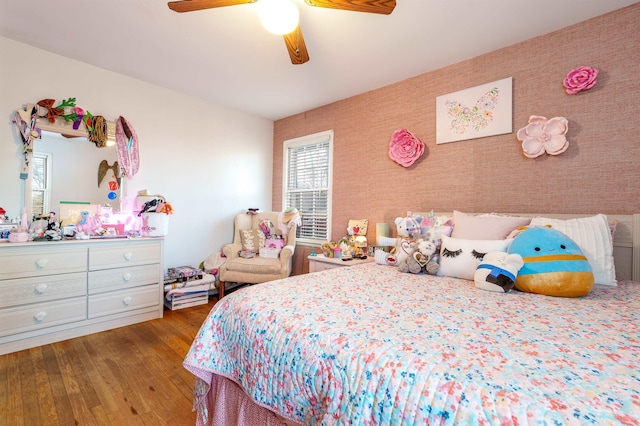 bedroom with wallpapered walls, ceiling fan, and wood finished floors