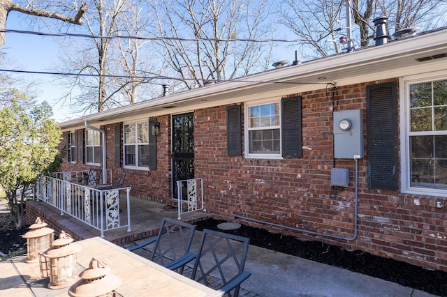 view of front of house featuring brick siding and a patio