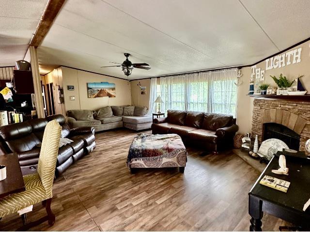 - living room with a ceiling fan, wood finished floors, and a stone fireplace