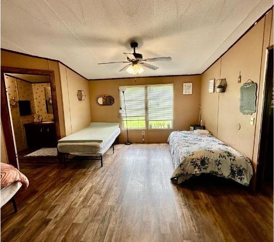  - bedroom featuring wood finished floors, a textured ceiling, ornamental molding, and a ceiling fan