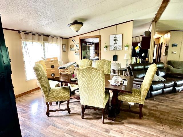  - dining room with wood finished floors, ornamental molding, a textured ceiling, and baseboards