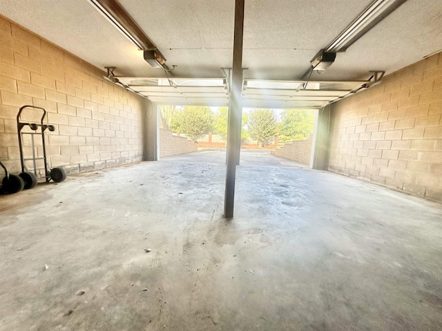  - garage featuring a garage door opener and concrete block wall