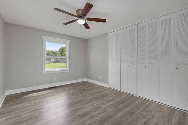  - unfurnished bedroom featuring wood finished floors, a closet, and a ceiling fan