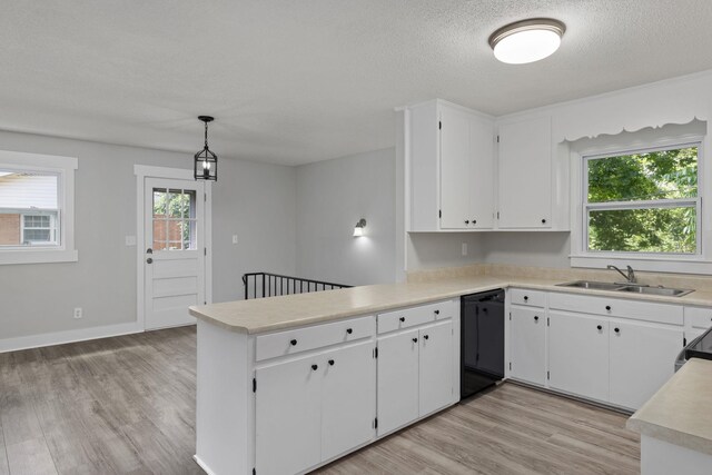  - kitchen featuring black dishwasher, a peninsula, light countertops, light wood finished floors, and a textured ceiling