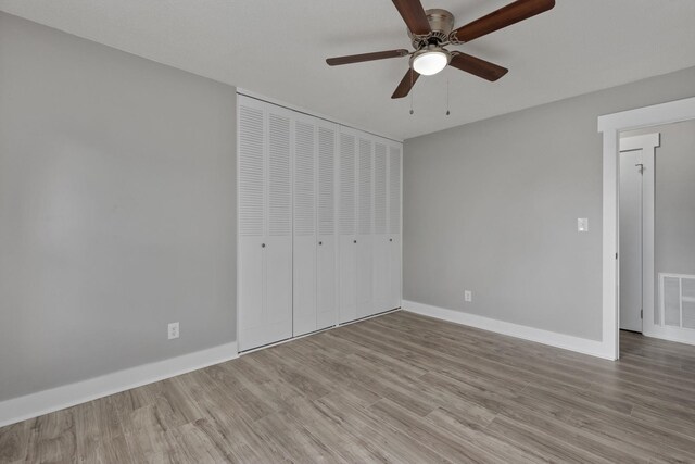  - unfurnished bedroom featuring wood finished floors, a closet, and a ceiling fan