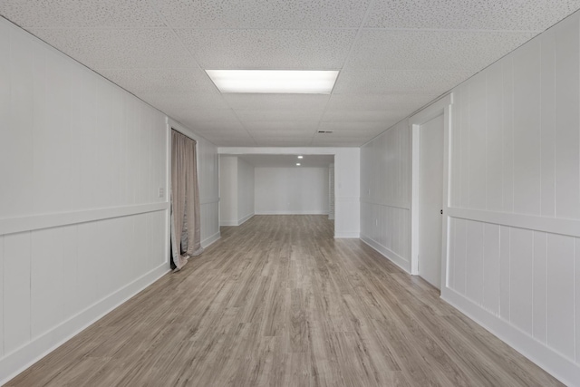  - unfurnished room featuring a decorative wall, wood finished floors, and a paneled ceiling
