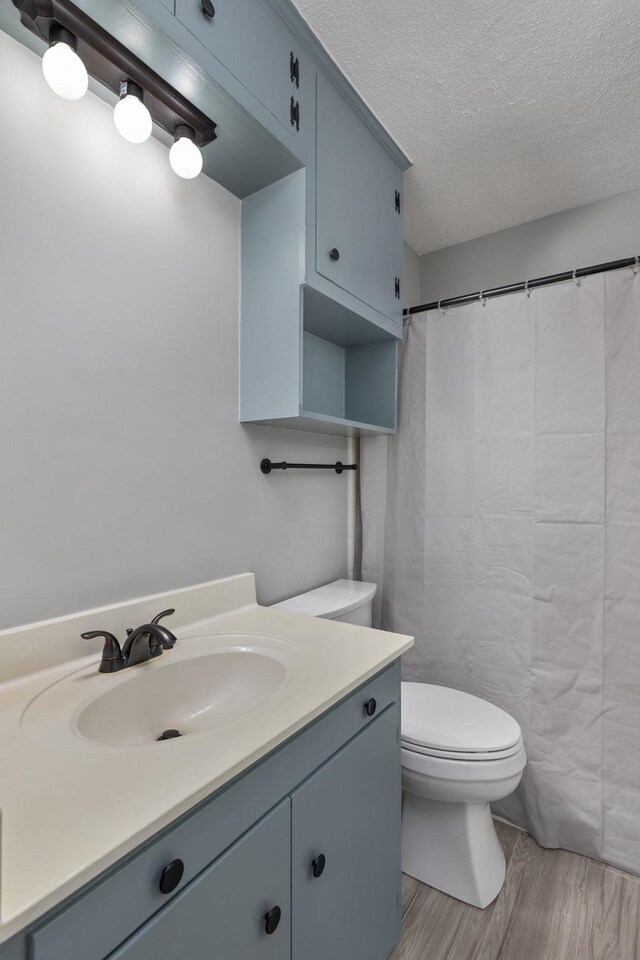  - full bath featuring vanity, wood finished floors, a textured ceiling, and a shower with curtain