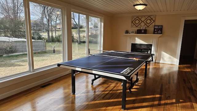 game room with a healthy amount of sunlight, crown molding, and a fireplace