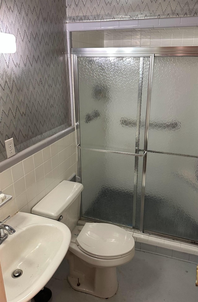 bathroom with sink, tile walls, an enclosed shower, and toilet